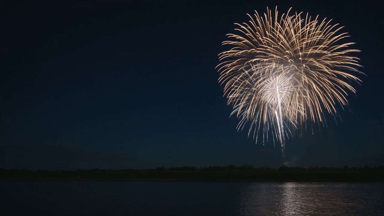 Golden and silver celebration fireworks reflected over a waterfront